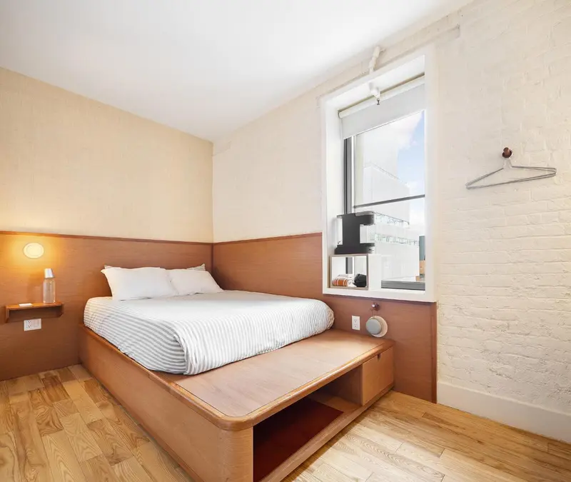 Une chambre lumineuse avec un lit encastré et un mur en briques blanches.