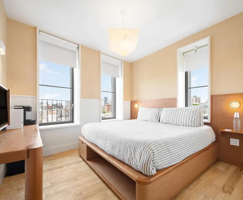Une chambre lumineuse avec un grand lit et une vue sur la ville.