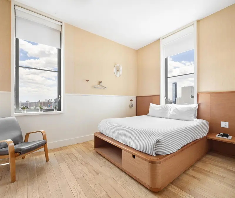 Une chambre lumineuse avec un lit double et un fauteuil.