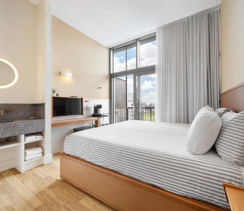 Une chambre lumineuse avec un grand lit et une vue sur la ville.