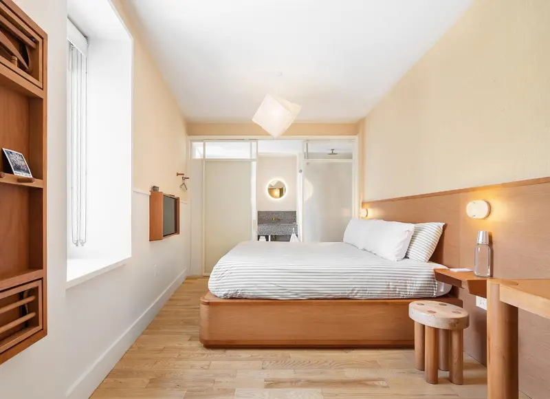 Chambre lumineuse avec un lit double et un mobilier en bois clair.