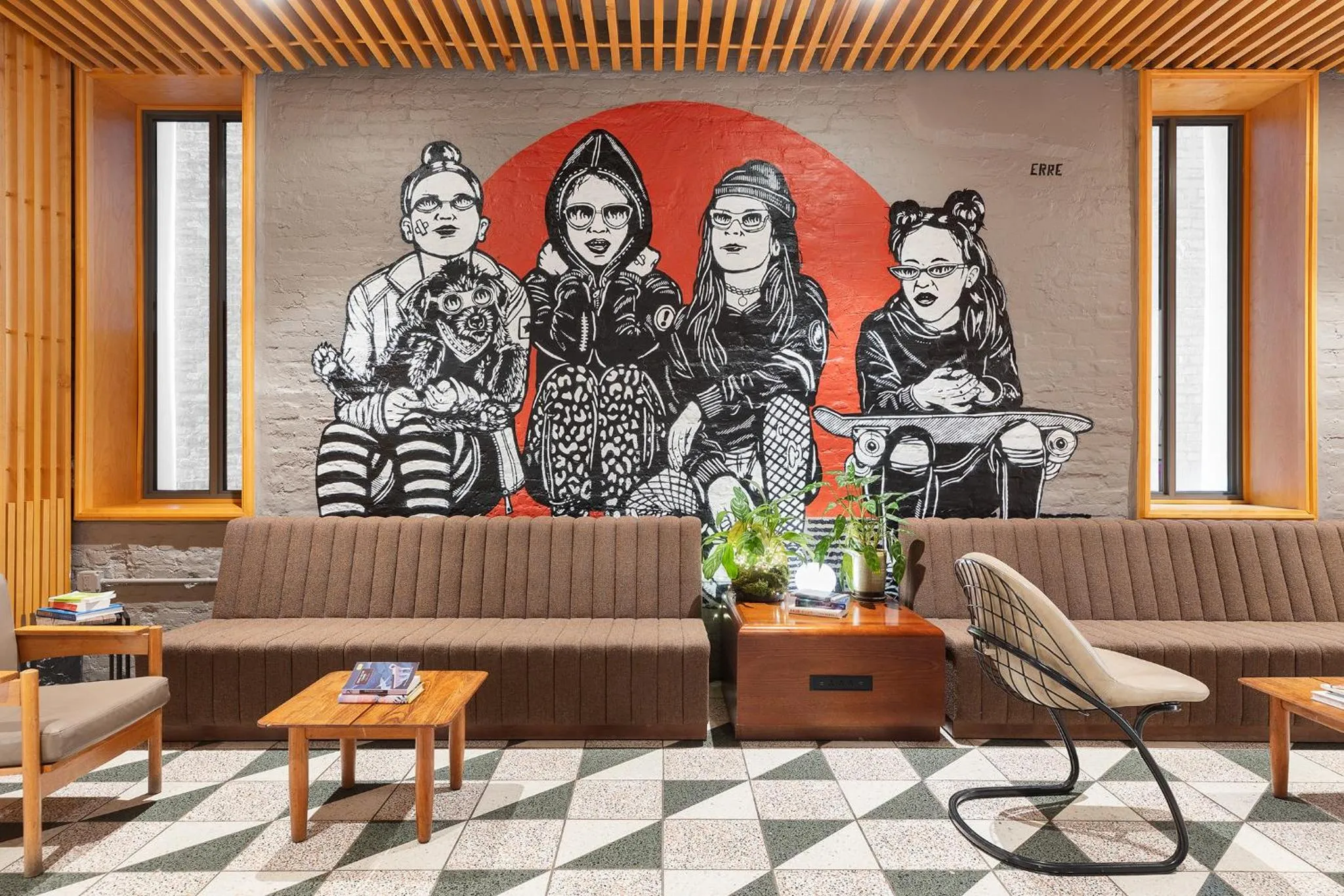 Un canapé marron est placé devant une fresque murale colorée dans un espace intérieur.