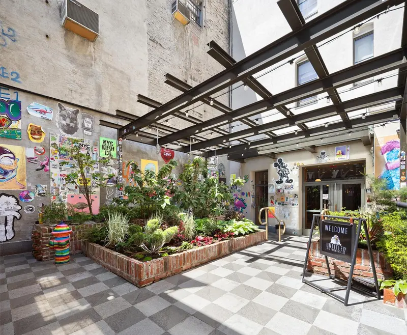 Une cour intérieure verdoyante avec des plantes et des œuvres d'art murales.