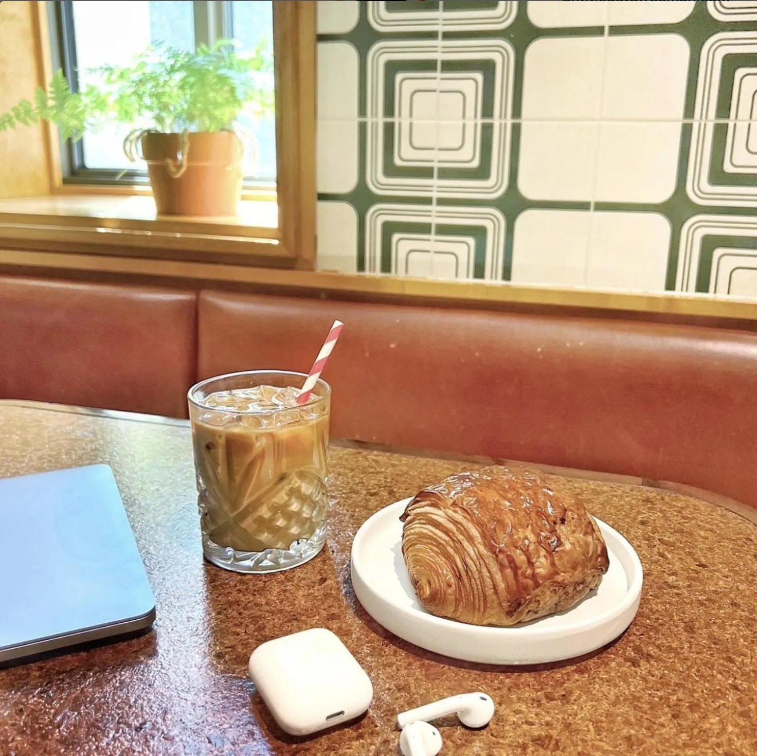 Un verre de boisson glacée et une viennoiserie sur une table.