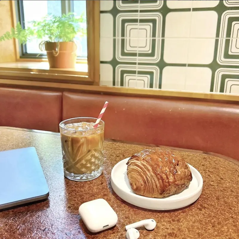 Un verre de boisson glacée et une viennoiserie sur une table.