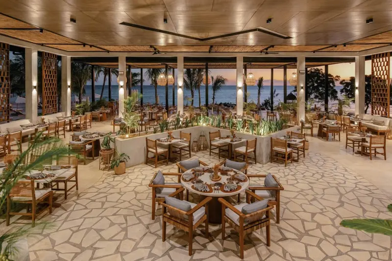 Une salle à manger lumineuse avec des tables dressées face à l'océan.