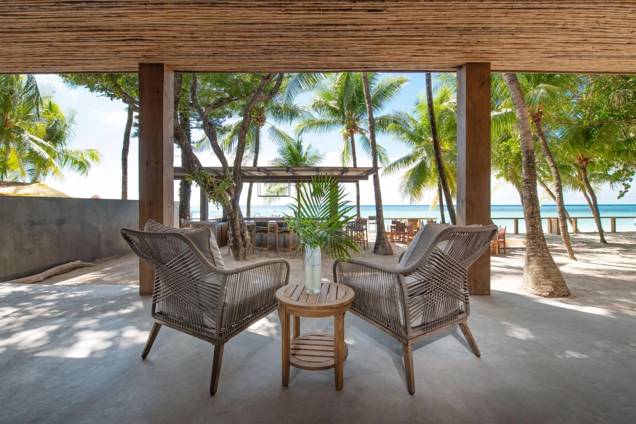 Espace de détente extérieur avec mobilier en rotin face à la mer.