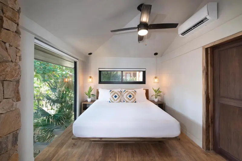 Une chambre lumineuse avec un grand lit et une vue sur la végétation.