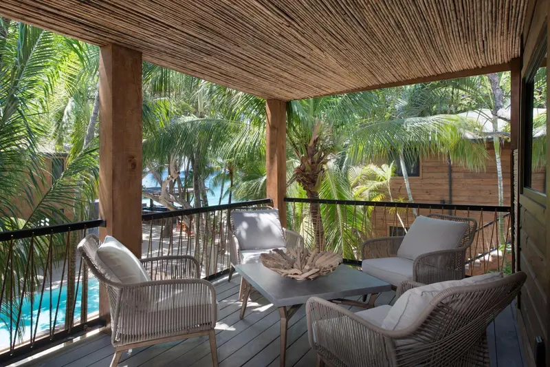 Espace de détente extérieur avec mobilier en rotin et vue sur la végétation.