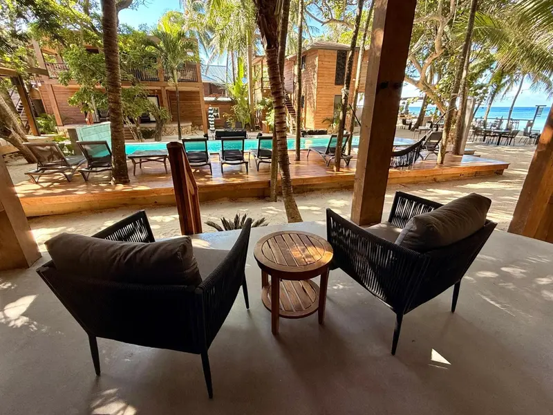 Espace de détente extérieur avec mobilier en osier et vue sur une piscine et la mer.