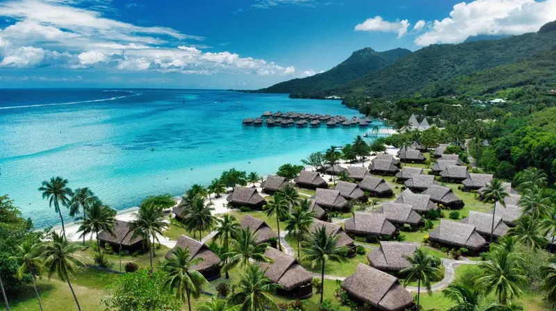 Vue aérienne d'un complexe hôtelier tropical au bord d'une eau turquoise.
