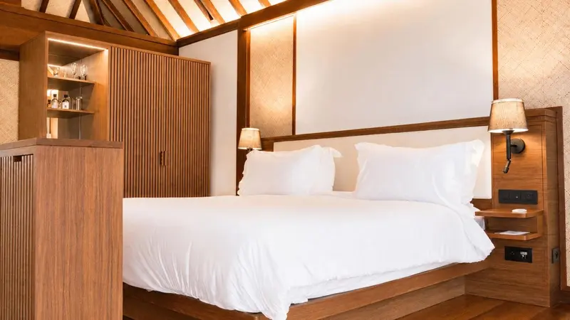 Une chambre lumineuse avec un grand lit recouvert de draps blancs.