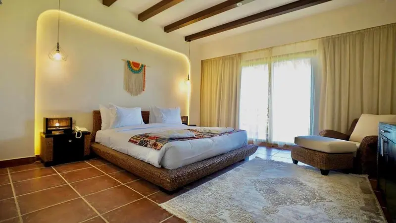 Une chambre lumineuse avec un grand lit et un coin salon.