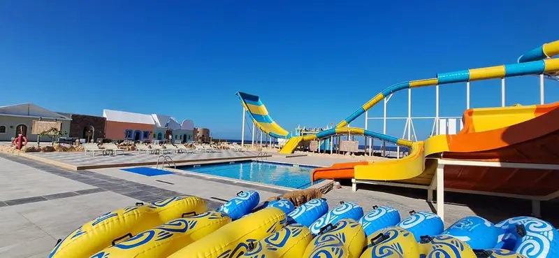 Une piscine avec des toboggans colorés et des transats.