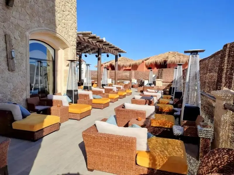 Terrasse aménagée avec des fauteuils et des transats sous des parasols.