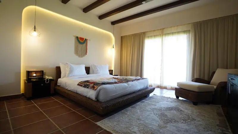 Une chambre lumineuse avec un grand lit et un coin salon.