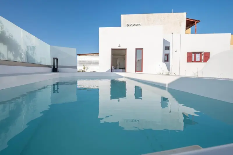 Piscine turquoise reflétant l'architecture blanche d'un bâtiment.