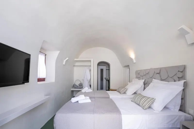 Une chambre lumineuse avec un grand lit et un téléviseur mural.