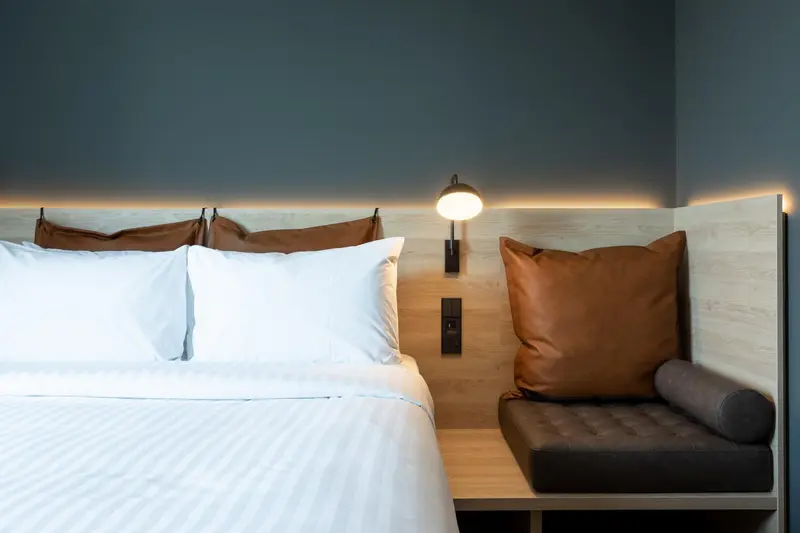 Un lit avec des oreillers blancs et des coussins marron dans une chambre.