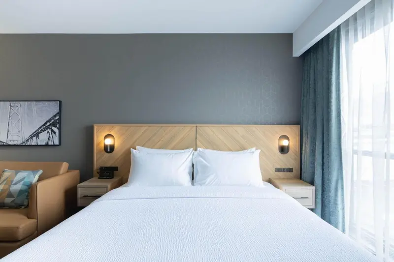 Une chambre d'hôtel lumineuse avec un grand lit et des tables de chevet.