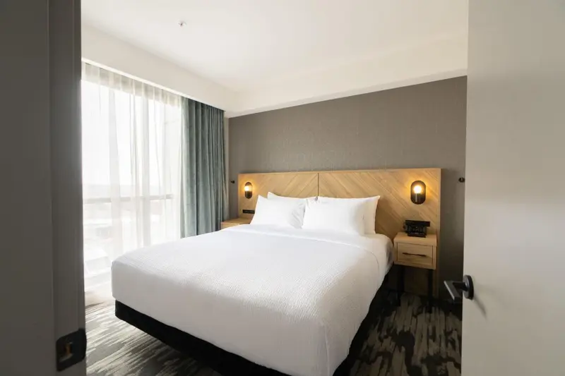 Une chambre lumineuse avec un grand lit recouvert de linge blanc.