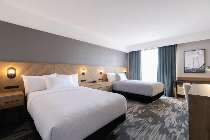 Une chambre d'hôtel moderne avec deux lits simples et des tables de chevet.