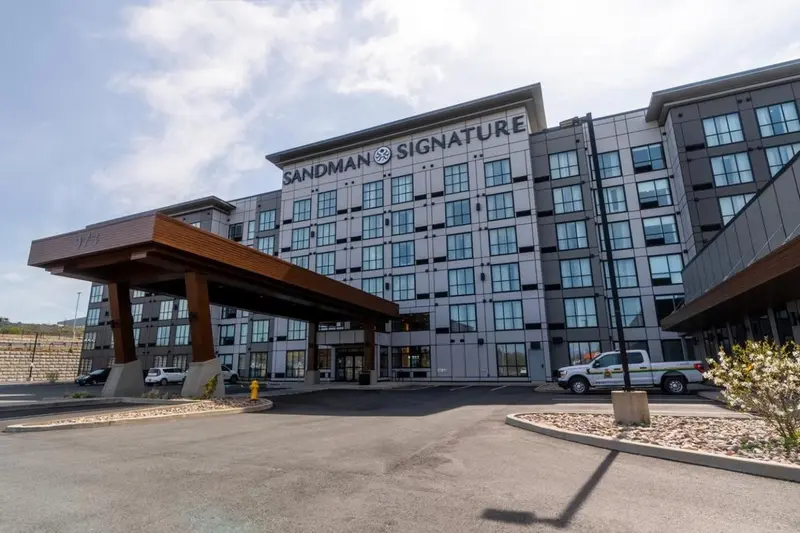 Façade d'un bâtiment moderne avec un auvent à l'entrée et un parking.