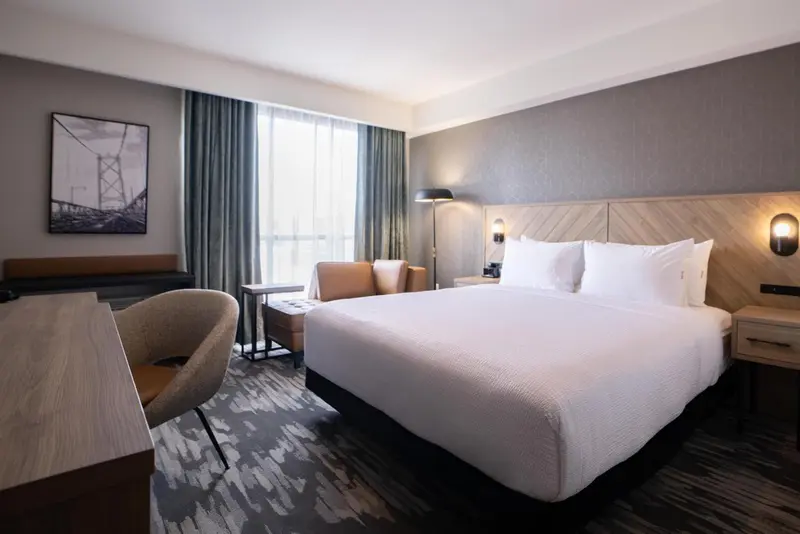 Une chambre d'hôtel moderne avec un grand lit et un coin salon près de la fenêtre.