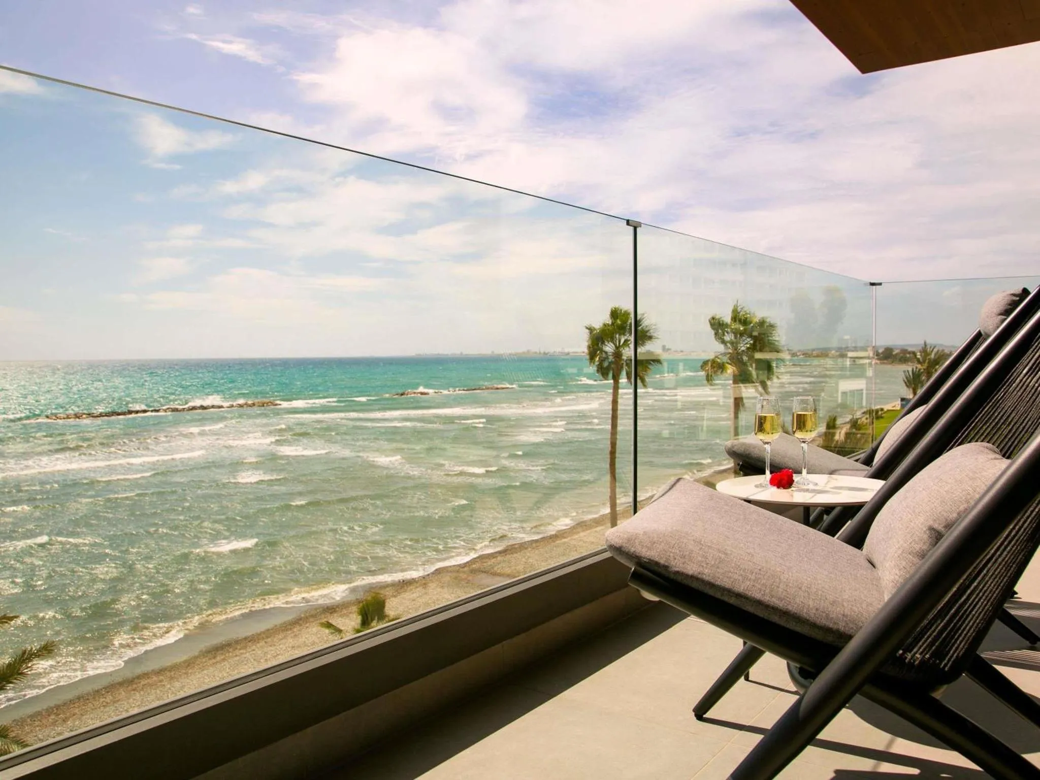 Transats et table basse sur une terrasse avec vue sur la mer.