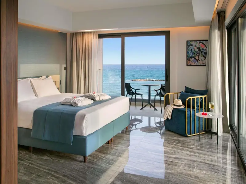 Chambre lumineuse avec un grand lit et vue sur la mer.