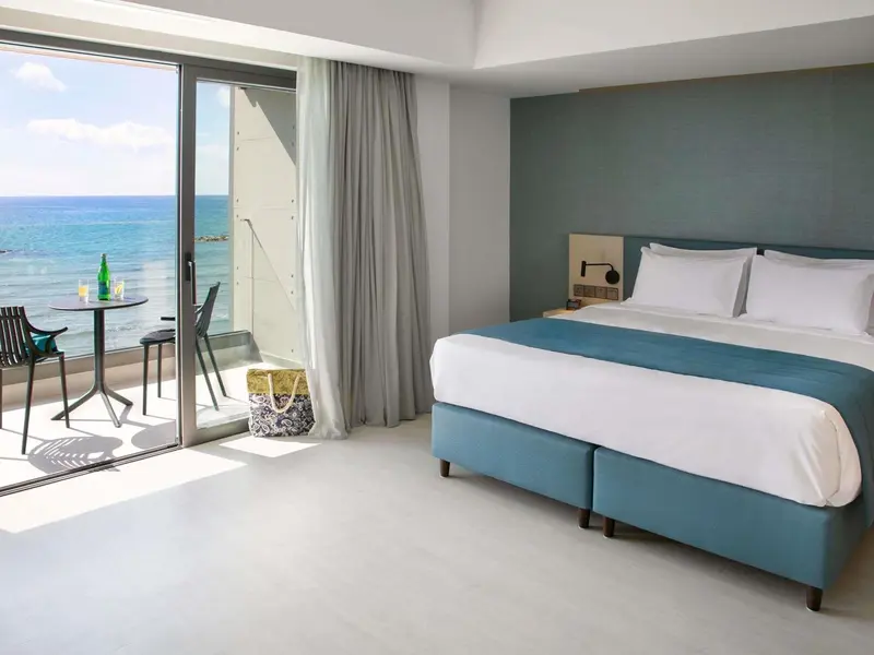 Une chambre lumineuse avec un lit confortable et un accès direct à une terrasse offrant une vue sur la mer.
