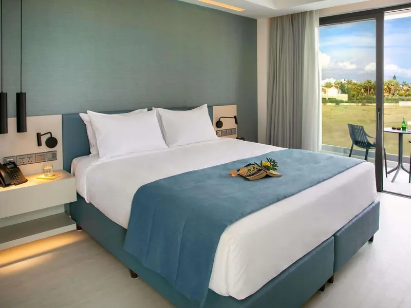 Une chambre lumineuse avec un grand lit et une vue sur un espace extérieur.