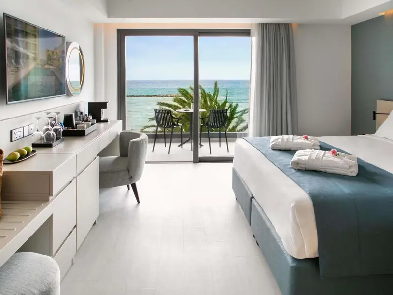 Chambre lumineuse avec vue sur la mer depuis une terrasse.