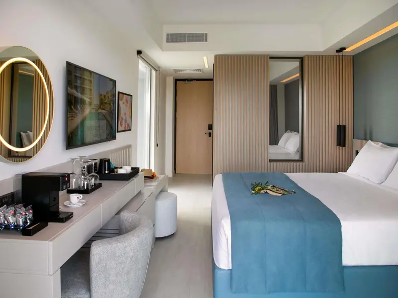 Chambre lumineuse avec un lit recouvert d'une courtepointe bleue et un espace bureau.