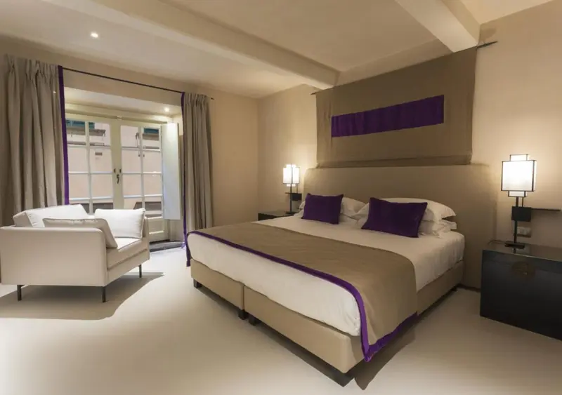 Une chambre lumineuse avec un lit et un coin salon donnant sur une terrasse.