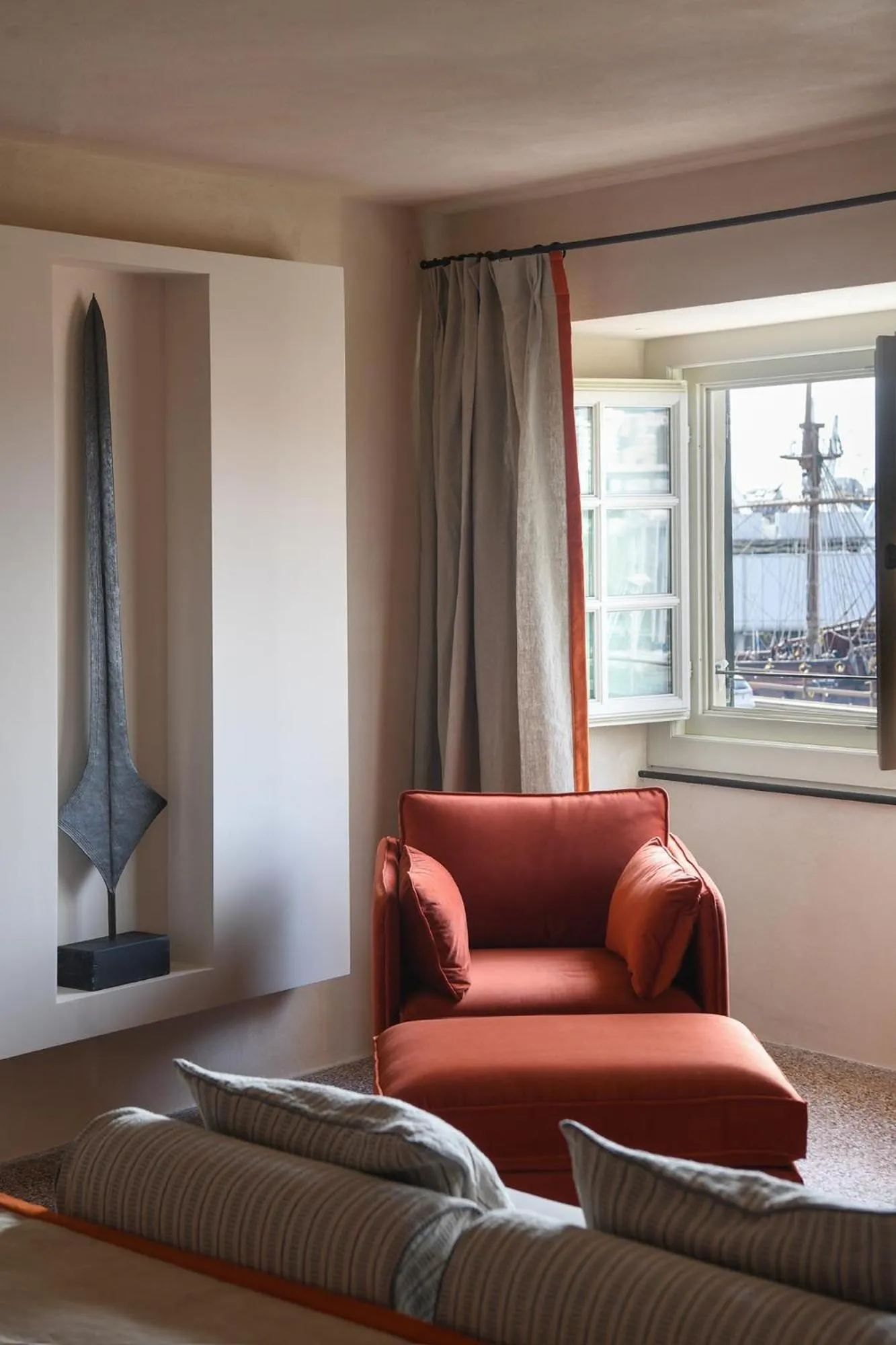 Un fauteuil rouge et un canapé se trouvent dans une pièce lumineuse avec une fenêtre.