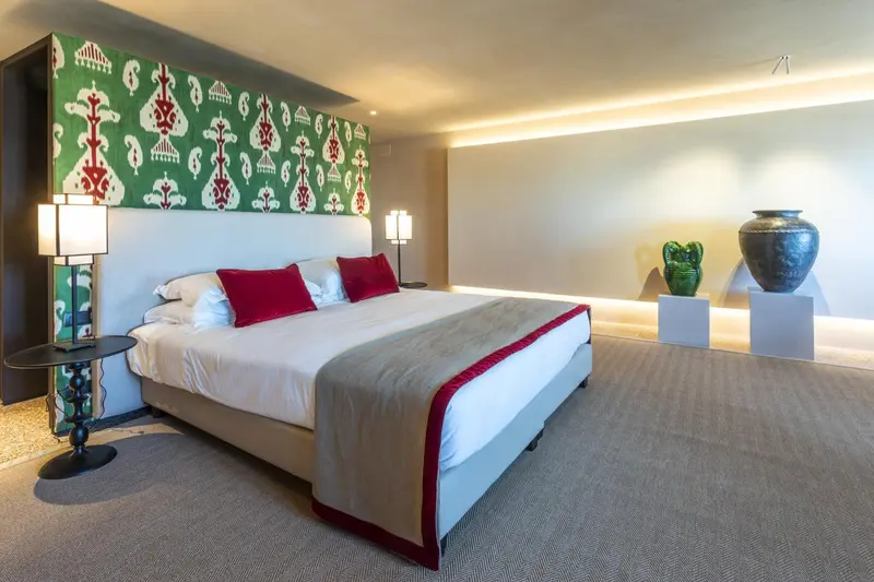 Une chambre lumineuse avec un grand lit et une décoration murale colorée.