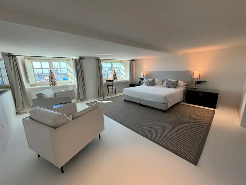 Une chambre lumineuse avec un grand lit et un coin salon.