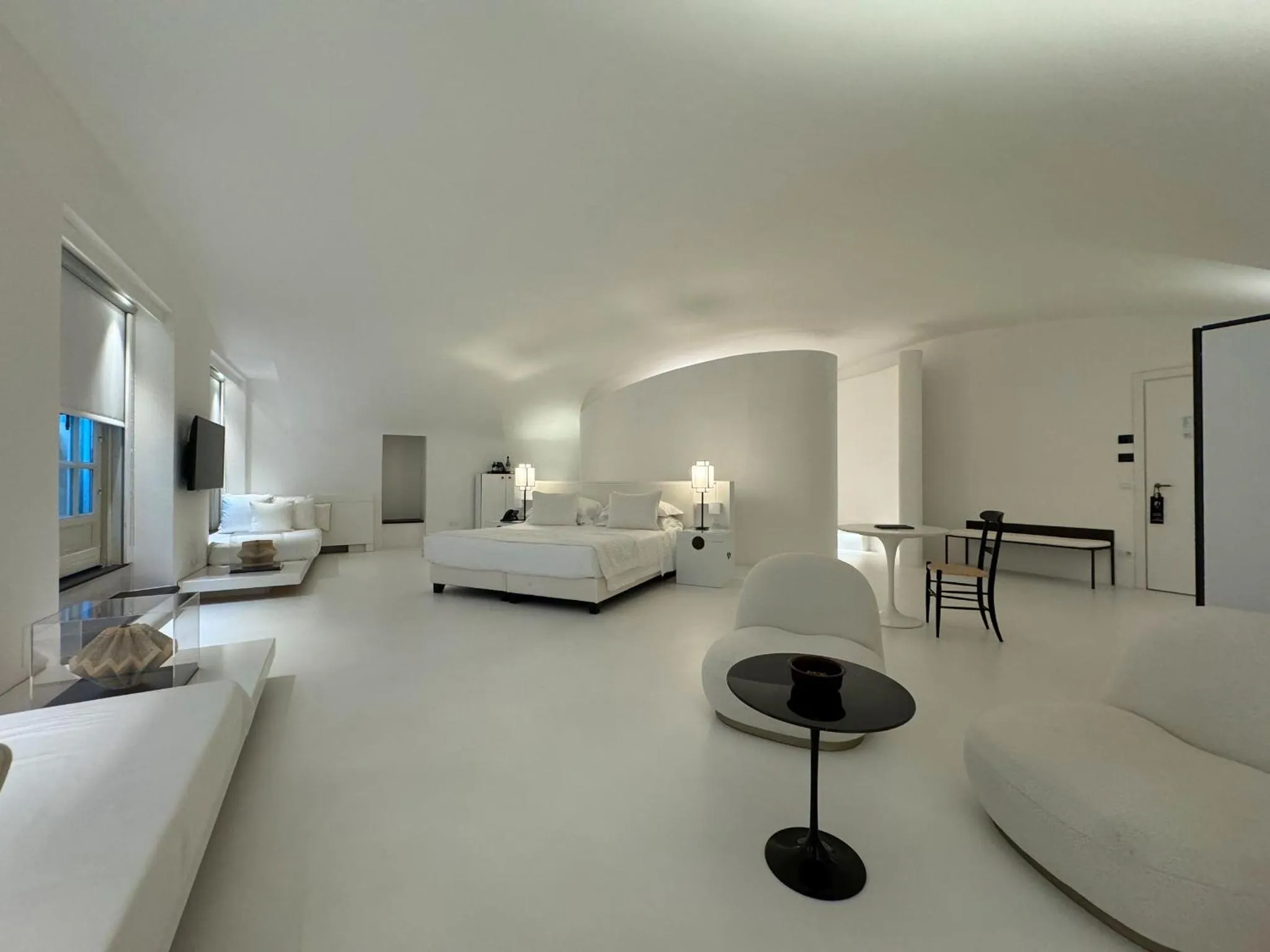 Espace de vie minimaliste et lumineux avec mobilier blanc et noir.