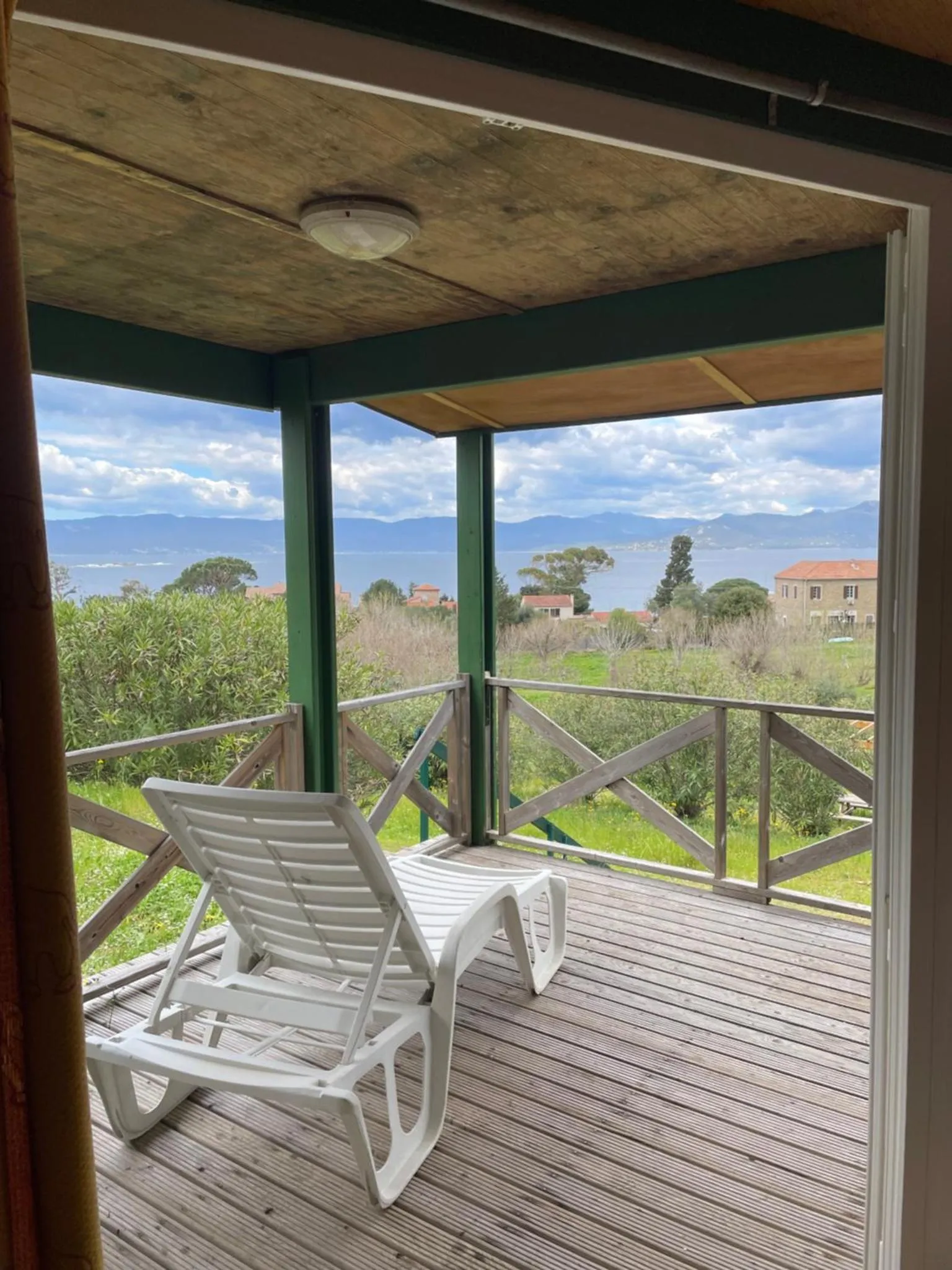 Terrasse avec transat et vue sur la mer et les montagnes.