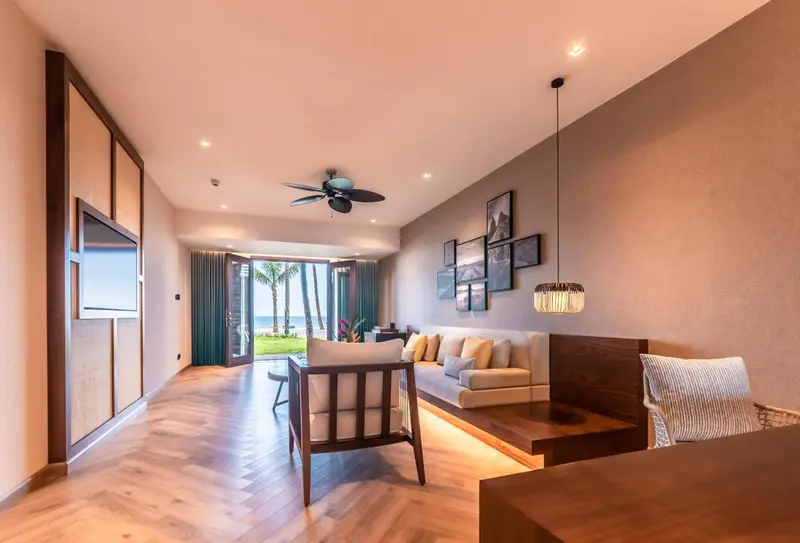 Espace de vie lumineux avec canapés et fauteuils en bois.