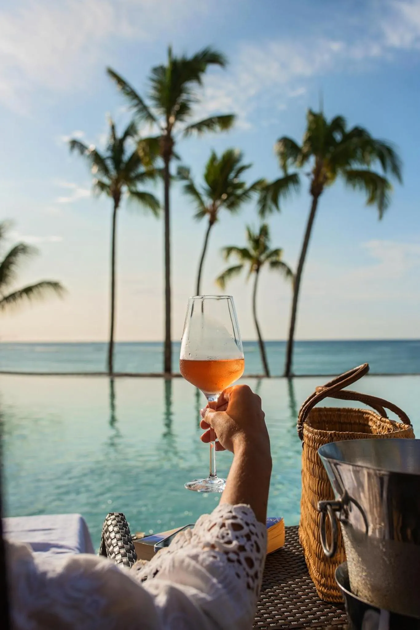 Un verre de boisson fraîche est posé au bord d'une piscine face à la mer.