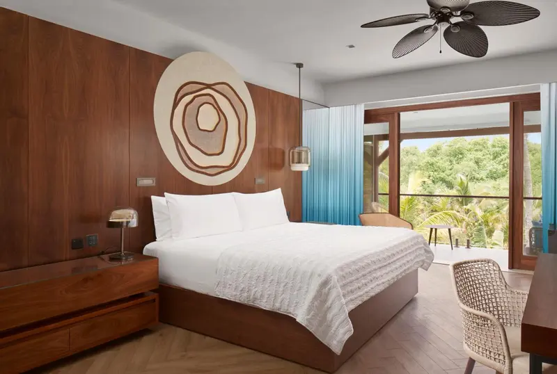 Une chambre lumineuse avec un grand lit et une vue sur la végétation.