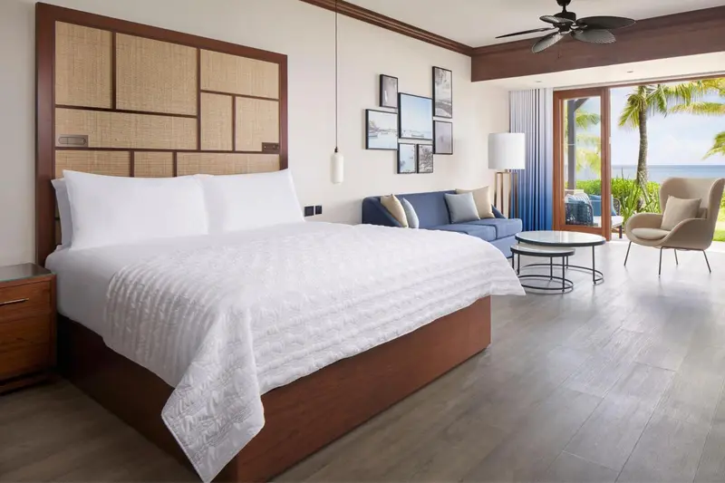 Une chambre lumineuse avec un grand lit et un espace salon.