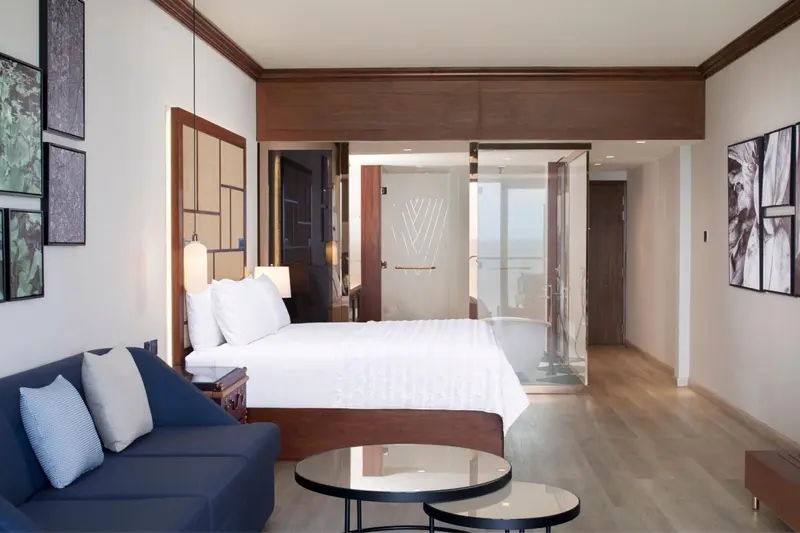 Une chambre lumineuse avec un grand lit et un coin salon.