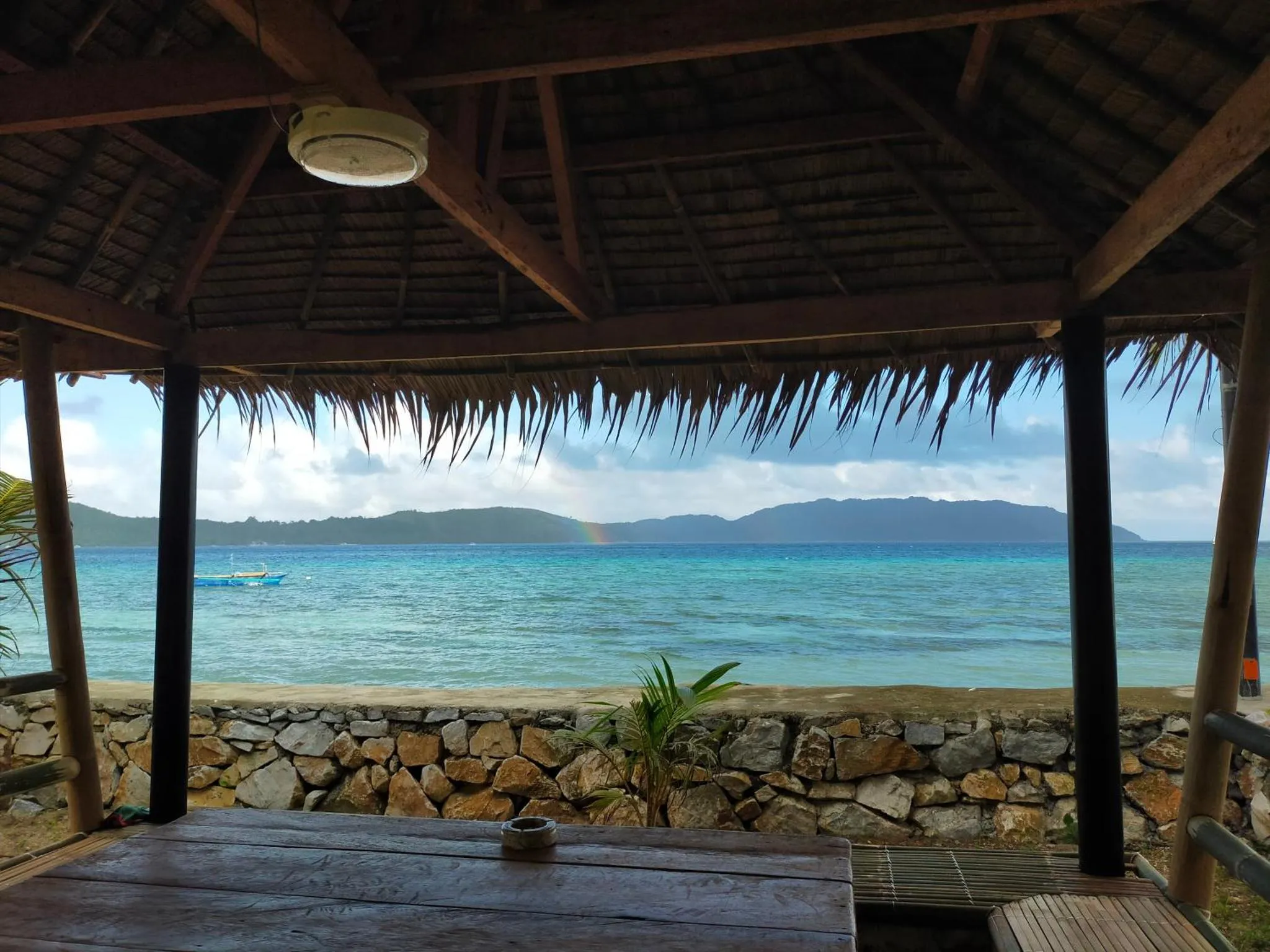Vue sur la mer depuis une structure abritée en bois et en chaume.