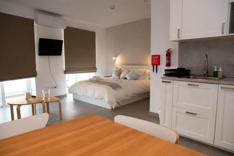 Une chambre lumineuse avec un lit double et une kitchenette.