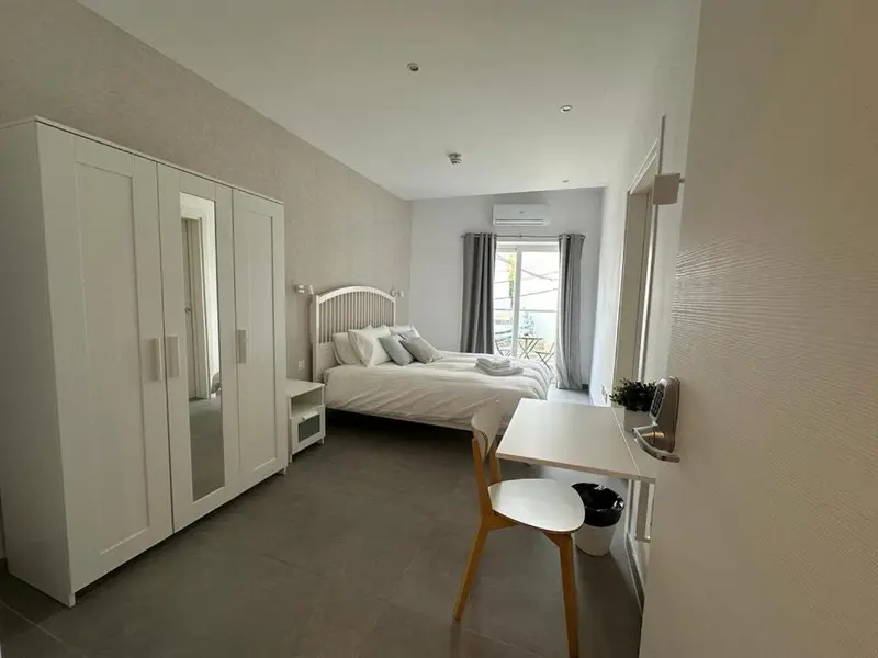 Une chambre lumineuse avec un grand lit et un bureau.
