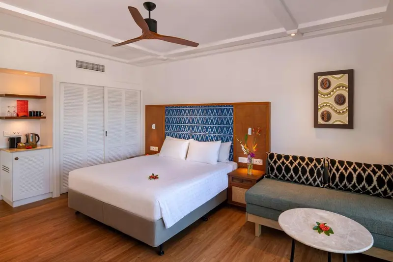 Une chambre lumineuse avec un grand lit et un coin salon.