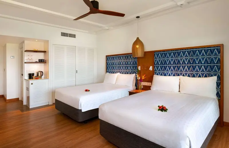 Une chambre lumineuse avec deux lits simples et une décoration murale en bois.